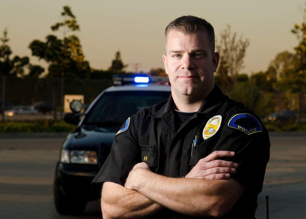 A cop posing with his car behind him