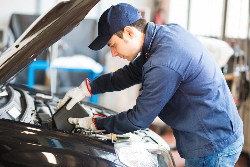 Man in blue uniform doing automotive Servicing