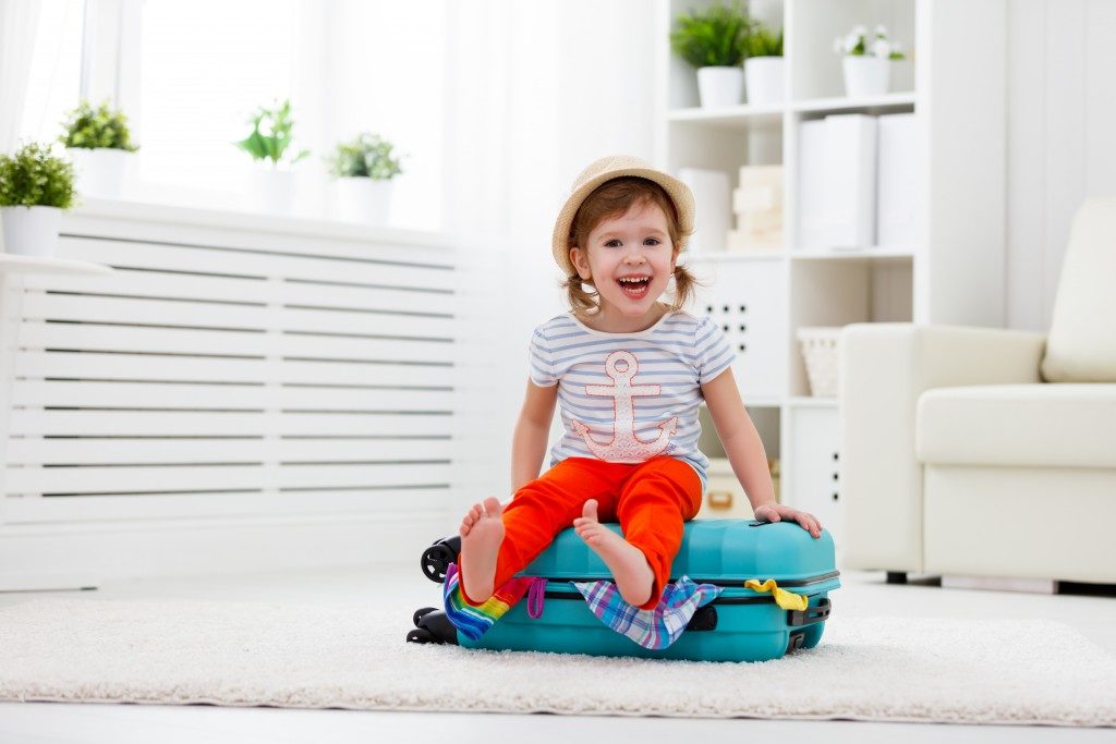Kid sitting on a luggage filled with clothes