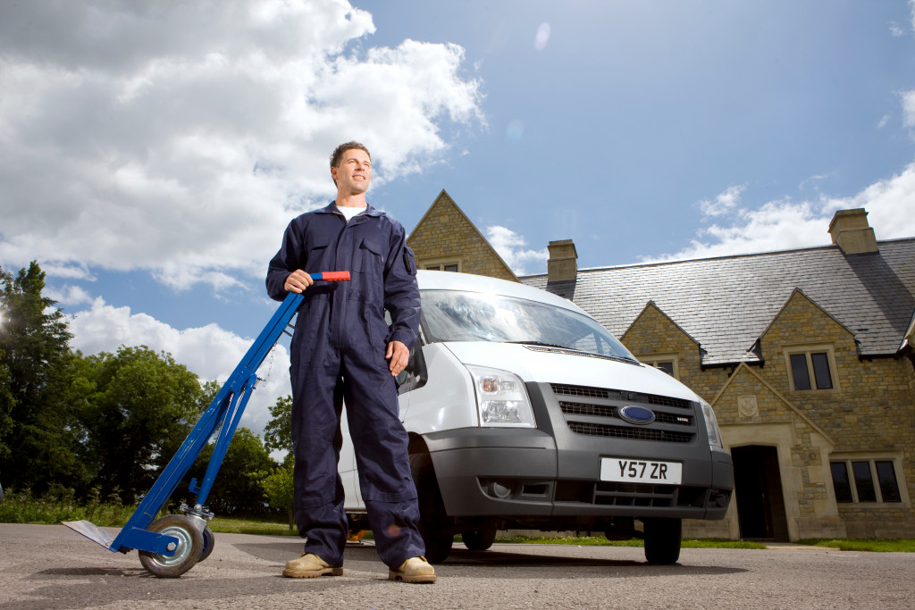 man standing in font of a van with a hand truck