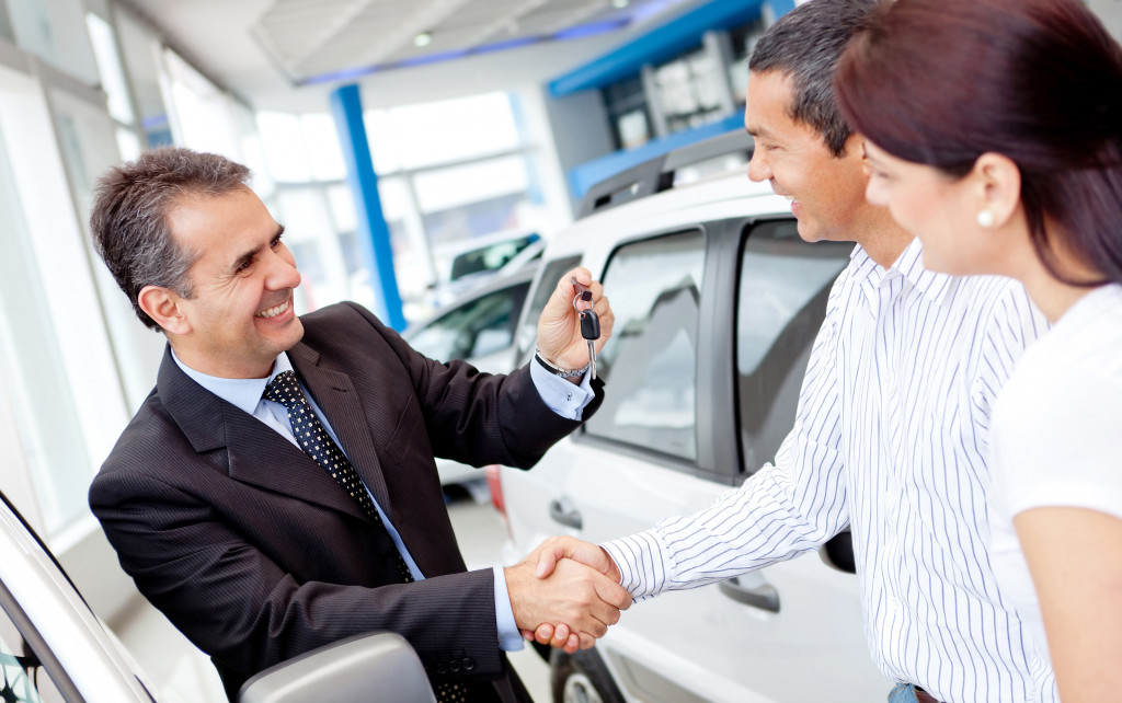 Couple buying a car and salesman handling keys