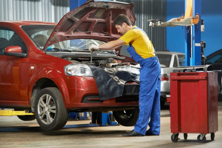 A mechanic working on a red vehicle in a garage