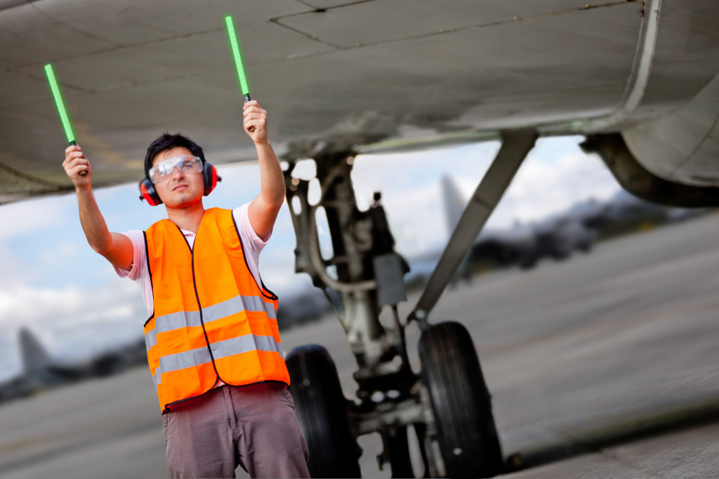 A man in a reflective vest holding light sticks for air traffic