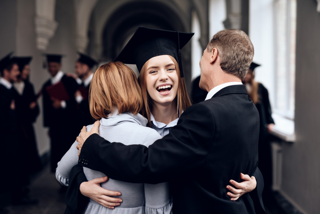 parents embracing their newly grad daughter